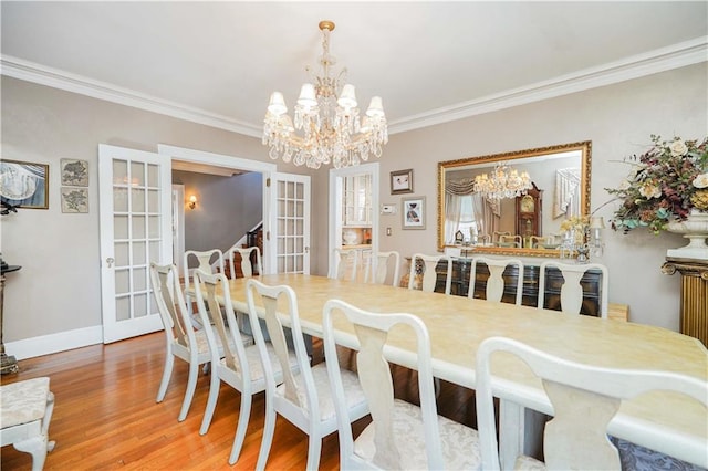 dining room with crown molding, baseboards, french doors, an inviting chandelier, and wood finished floors