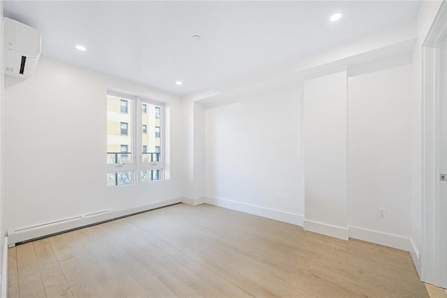 empty room featuring a baseboard radiator, a wall mounted AC, and light wood-type flooring