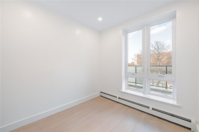 unfurnished room with a baseboard radiator and light hardwood / wood-style floors