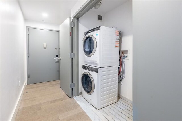 washroom featuring stacked washer / drying machine and light hardwood / wood-style floors