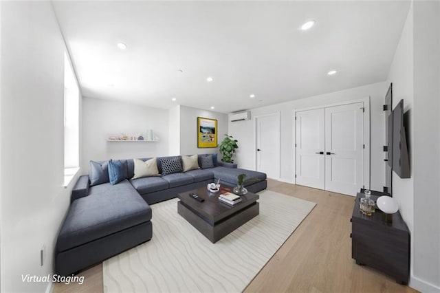 living room with an AC wall unit and light hardwood / wood-style floors