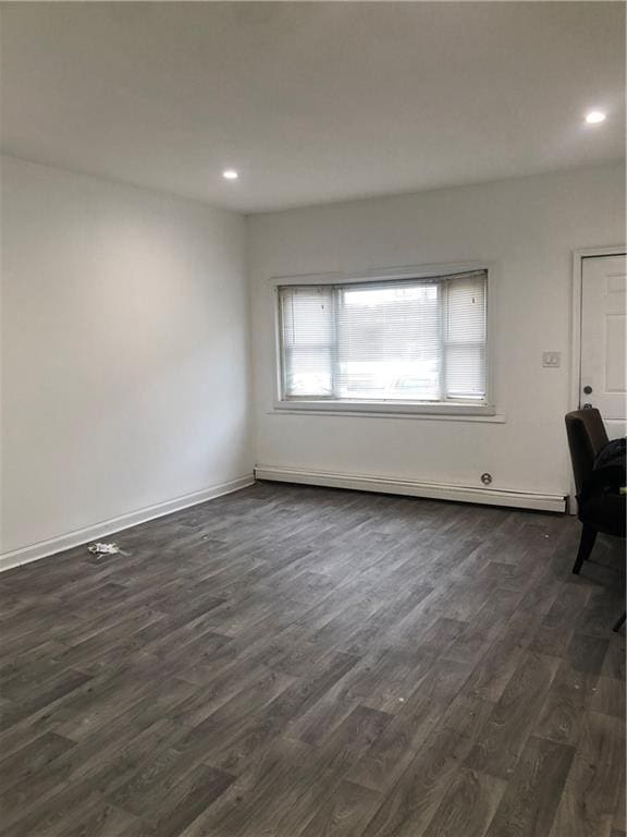 spare room featuring dark wood-style floors, baseboard heating, baseboards, and recessed lighting