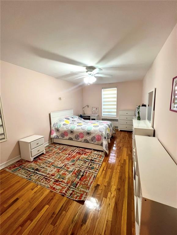 bedroom with radiator, wood-type flooring, and ceiling fan