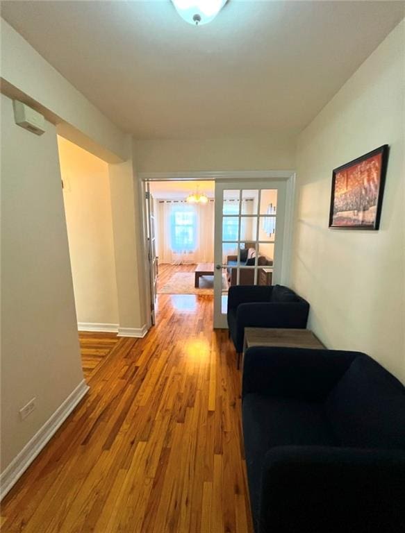 hall with french doors, wood finished floors, and baseboards