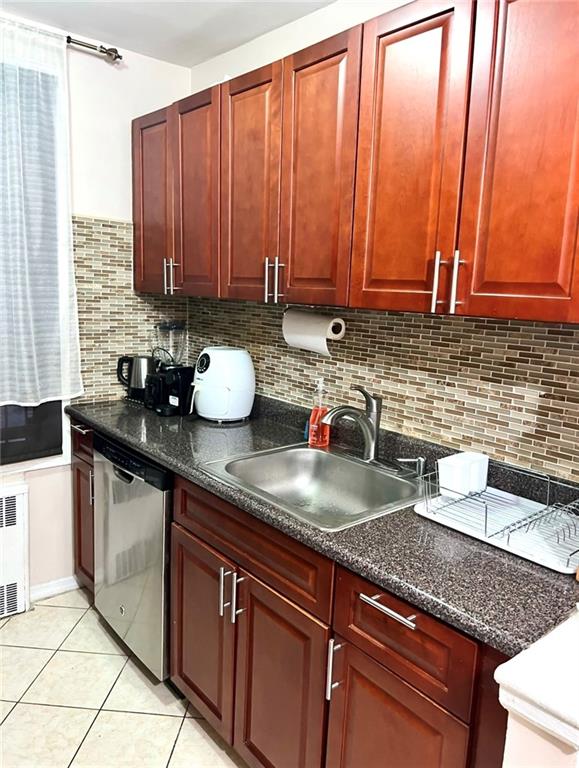 kitchen with tasteful backsplash, stainless steel dishwasher, sink, and light tile patterned floors