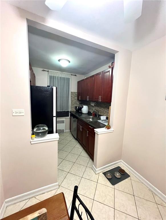 kitchen with sink, light tile patterned floors, radiator heating unit, stainless steel appliances, and backsplash