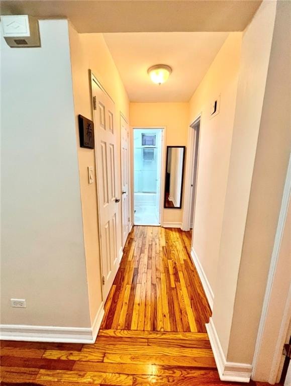 corridor with light wood-type flooring and baseboards