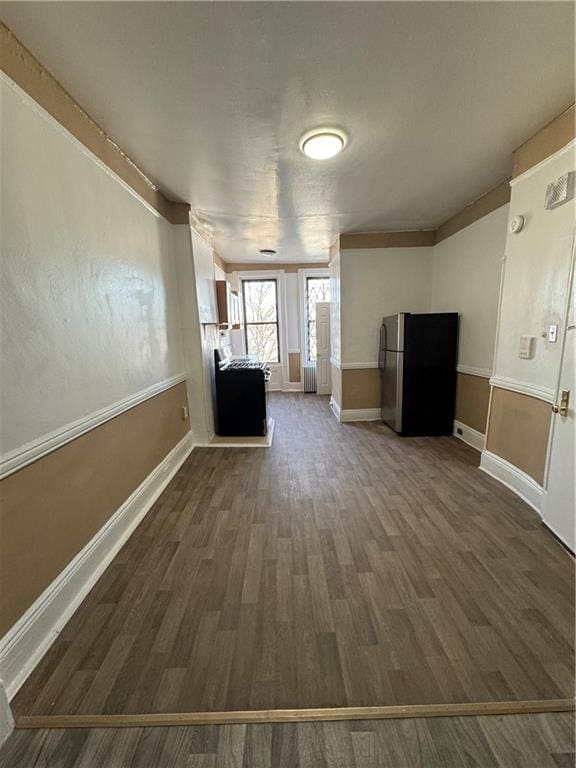 basement with dark wood-type flooring and stainless steel fridge