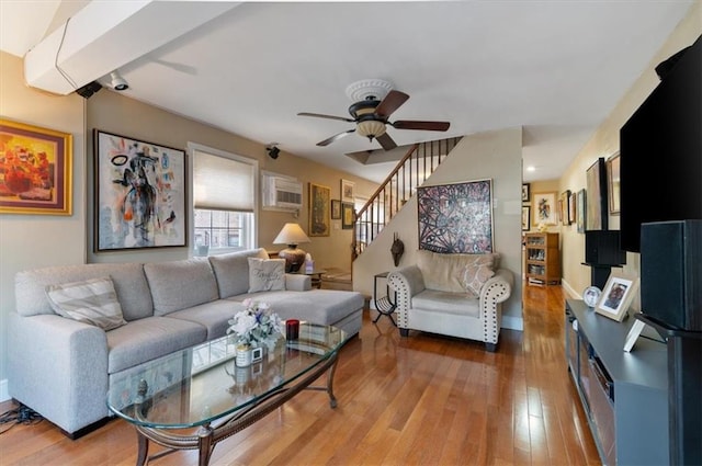 living room featuring wood-type flooring, a wall mounted AC, and ceiling fan