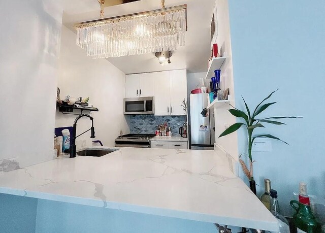 kitchen featuring white cabinetry, sink, light stone countertops, and appliances with stainless steel finishes