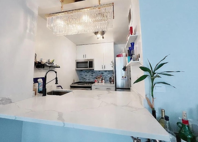 kitchen featuring light stone counters, appliances with stainless steel finishes, decorative backsplash, and a sink