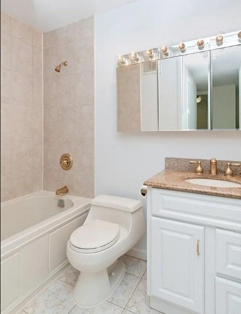 full bathroom featuring tile patterned floors, vanity, toilet, and tiled shower / bath combo