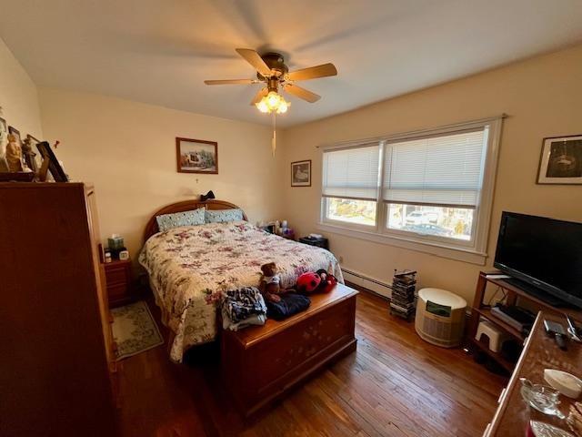 bedroom with dark hardwood / wood-style flooring, a baseboard radiator, and ceiling fan