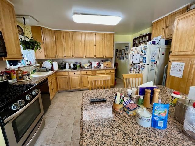 kitchen with light tile patterned floors, sink, dishwasher, white refrigerator, and gas stove