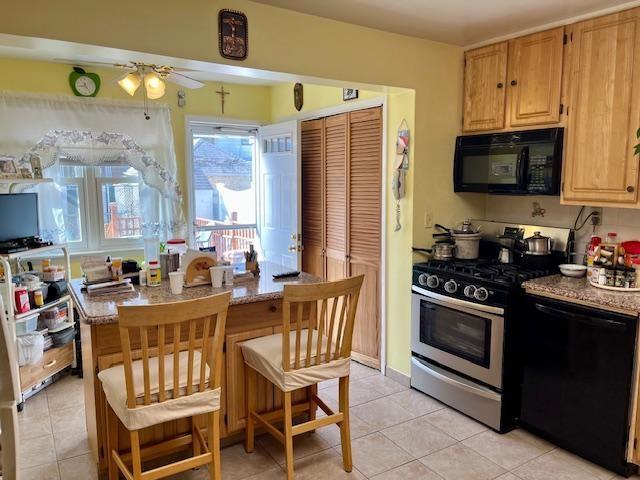 kitchen with light stone countertops, light tile patterned floors, black appliances, and ceiling fan