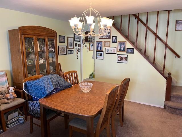 carpeted dining area with a notable chandelier