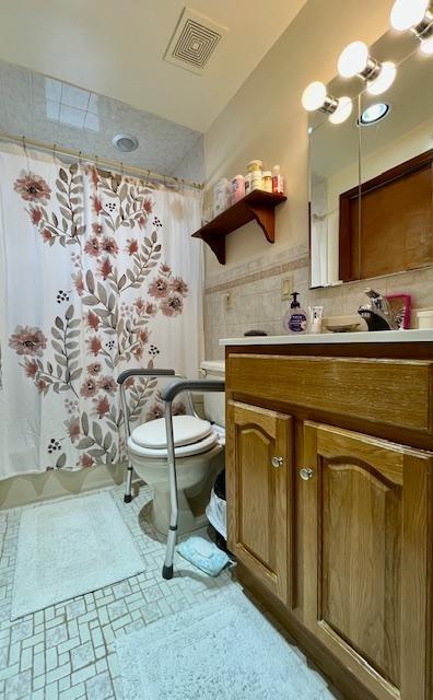 bathroom with vanity, tile walls, and toilet