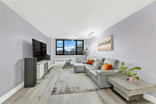 living area with baseboards, light wood-type flooring, and radiator