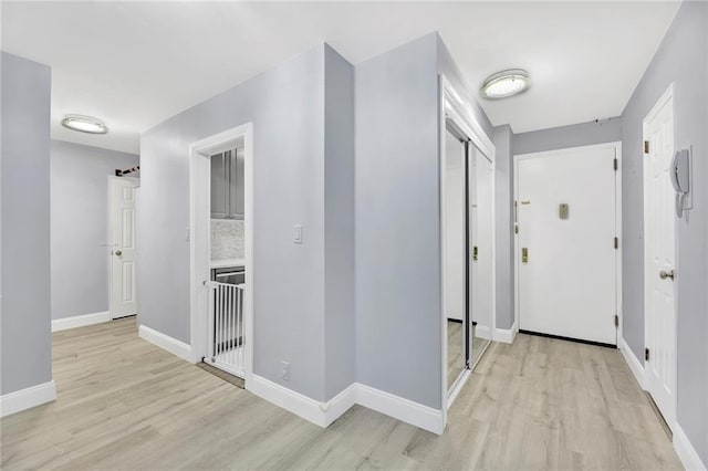 corridor with baseboards and light wood finished floors