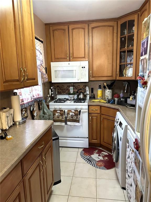 kitchen with tasteful backsplash, washer / clothes dryer, white appliances, and light tile patterned floors