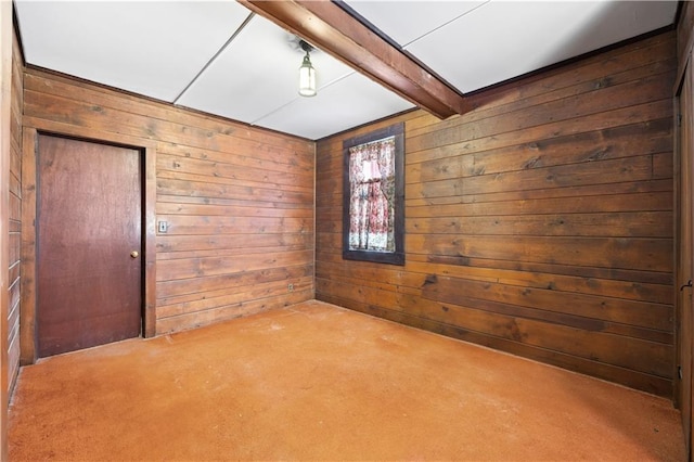 spare room with beam ceiling, carpet, and wood walls