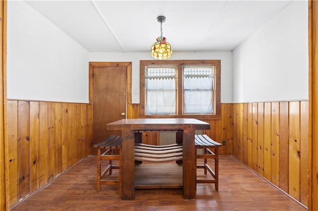 dining area featuring wood-type flooring and wooden walls