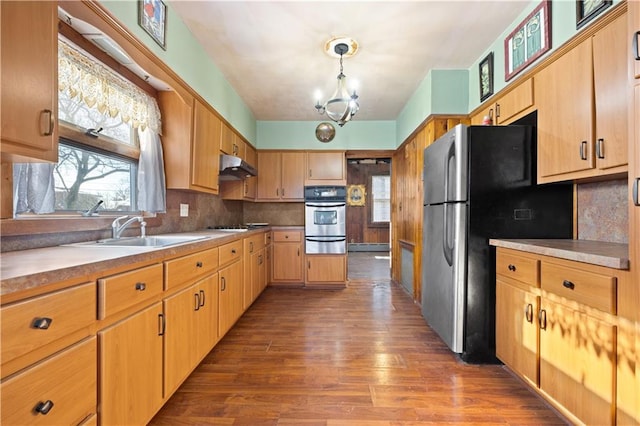 kitchen with sink, an inviting chandelier, hanging light fixtures, stainless steel appliances, and backsplash