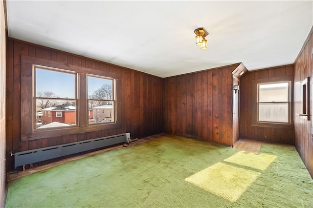 empty room with a baseboard radiator, wooden walls, and light carpet