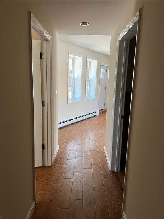 corridor with a baseboard radiator and light wood-type flooring