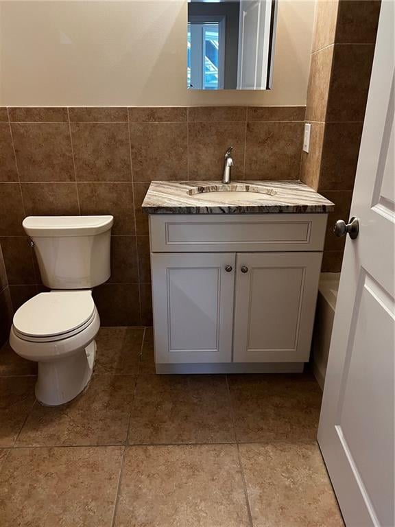 bathroom featuring tile patterned flooring, vanity, tile walls, and toilet