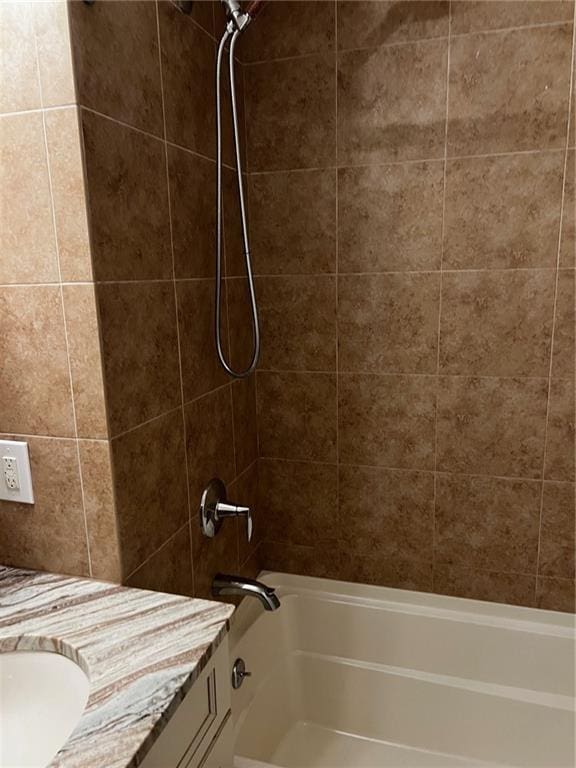 bathroom featuring vanity and tiled shower / bath