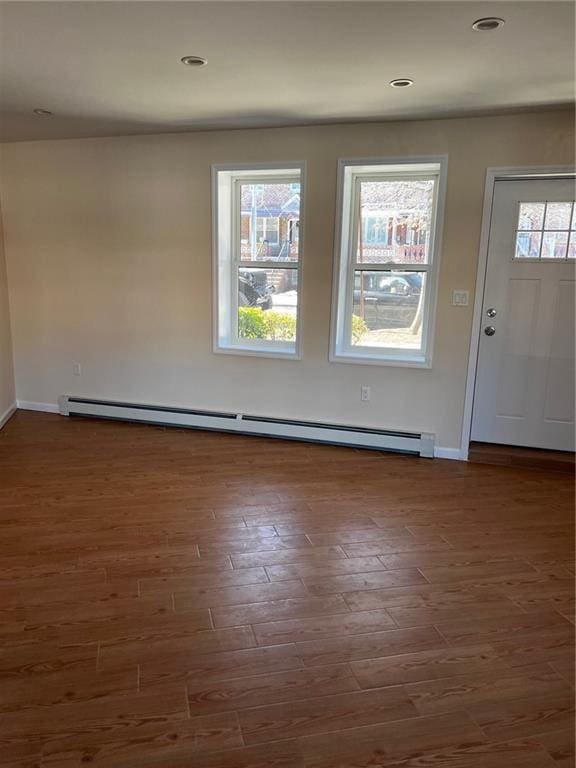 foyer entrance featuring a baseboard heating unit, plenty of natural light, and dark hardwood / wood-style floors