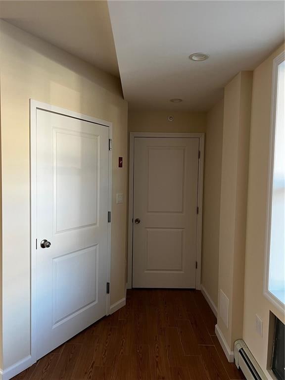 hall with dark wood-type flooring and baseboard heating