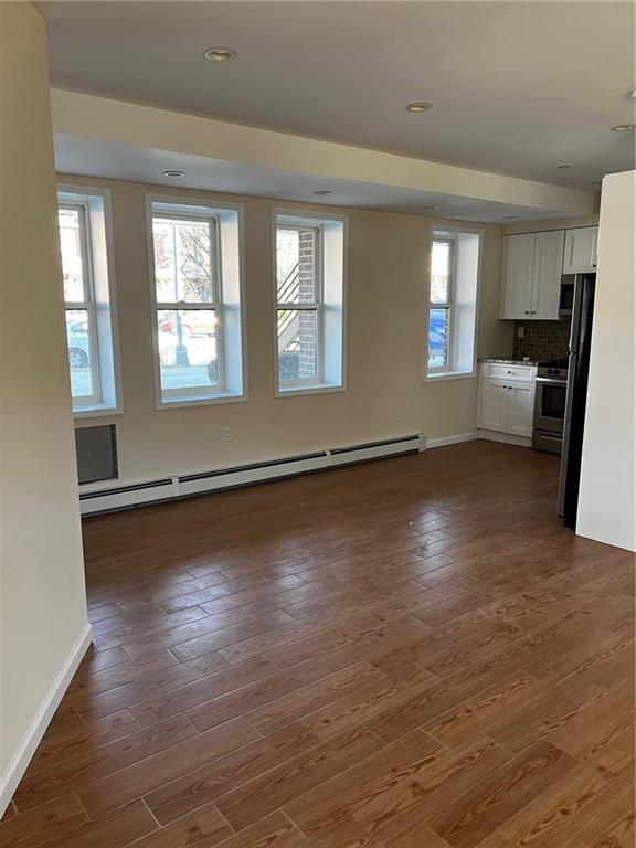 interior space with a baseboard heating unit and dark hardwood / wood-style floors