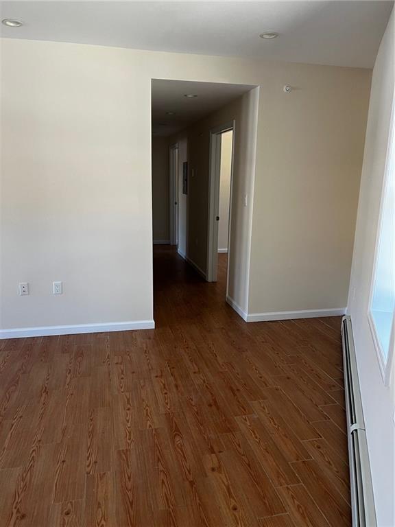 spare room with dark wood-type flooring and a baseboard heating unit