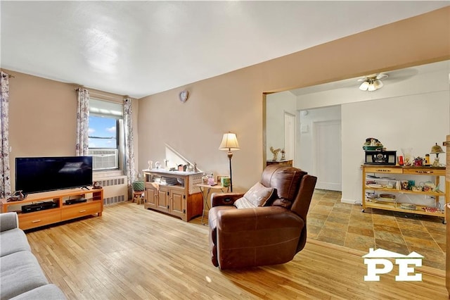 living room with cooling unit, radiator heating unit, and light hardwood / wood-style flooring