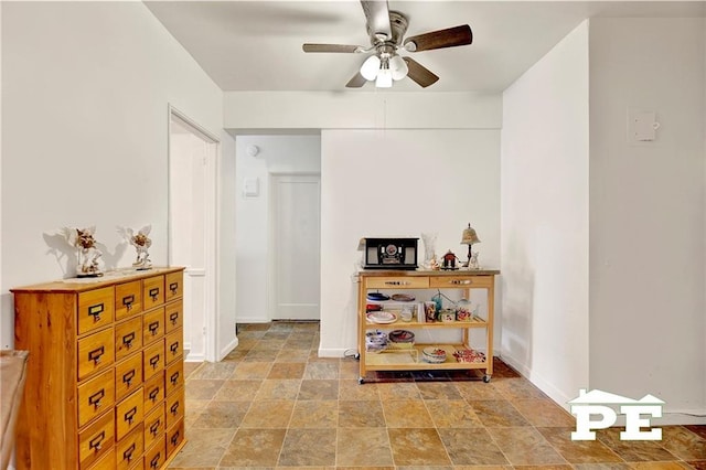 hall featuring stone finish flooring and baseboards