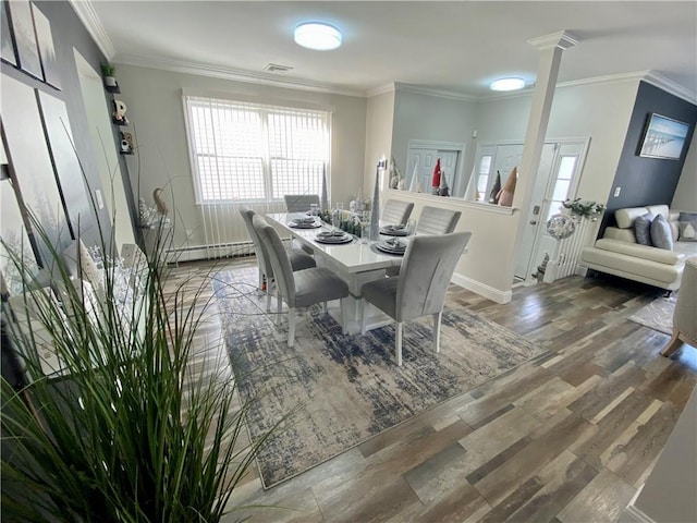 dining room with crown molding, baseboard heating, a wealth of natural light, and wood finished floors