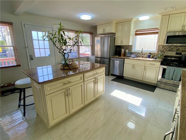 43 Lerer Ln, Staten Island, NY 10307 - kitchen with appliances with stainless steel finishes, cream cabinets, tasteful backsplash, a center island, and a kitchen bar