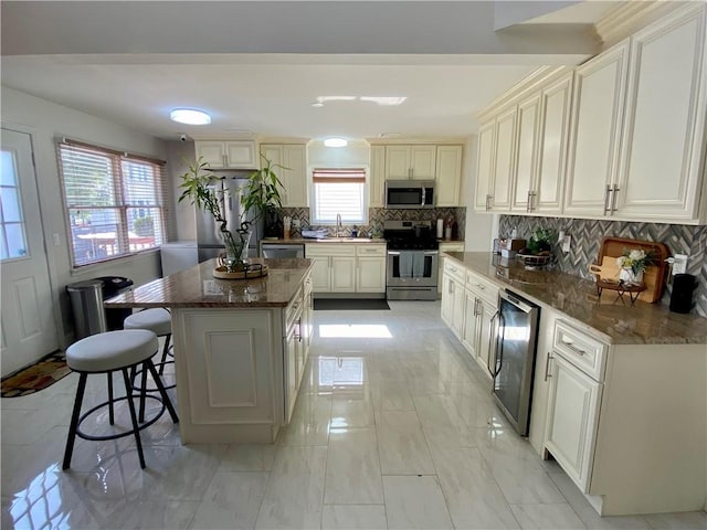 kitchen with a sink, stainless steel appliances, a kitchen breakfast bar, tasteful backsplash, and a kitchen island