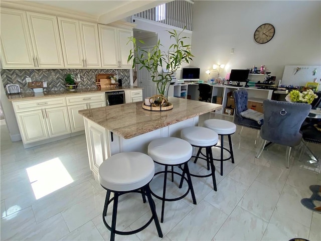 kitchen featuring light stone counters, tasteful backsplash, beverage cooler, a kitchen island, and a kitchen bar