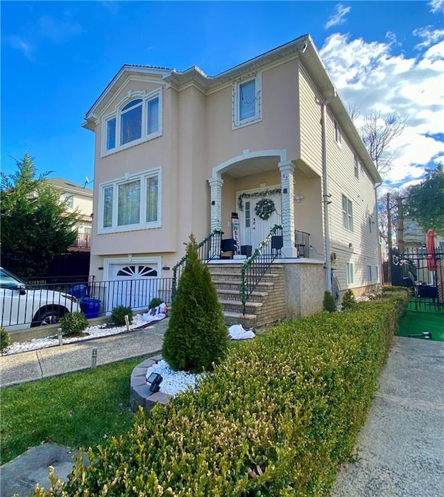 view of front facade with a garage, stucco siding, and fence