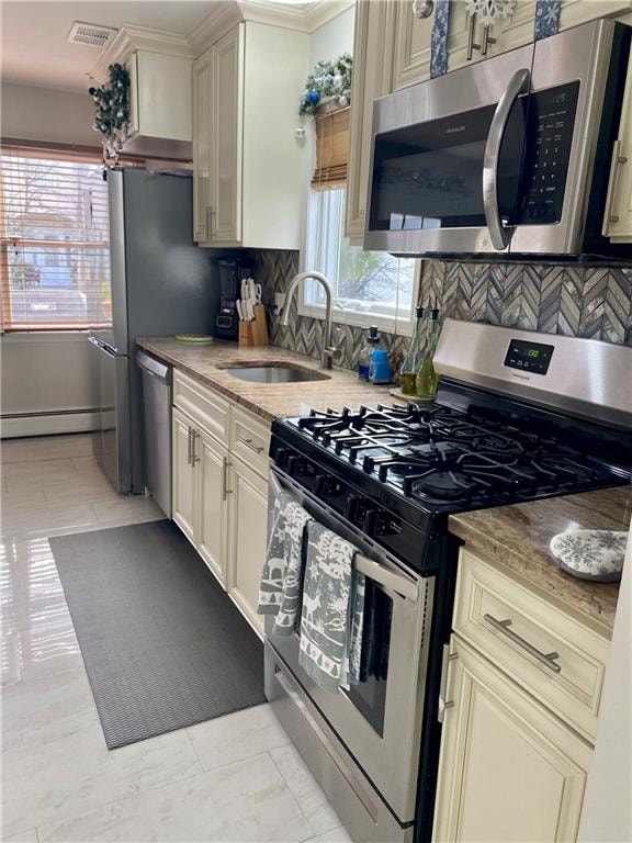 kitchen with decorative backsplash, stainless steel appliances, a baseboard heating unit, a sink, and visible vents