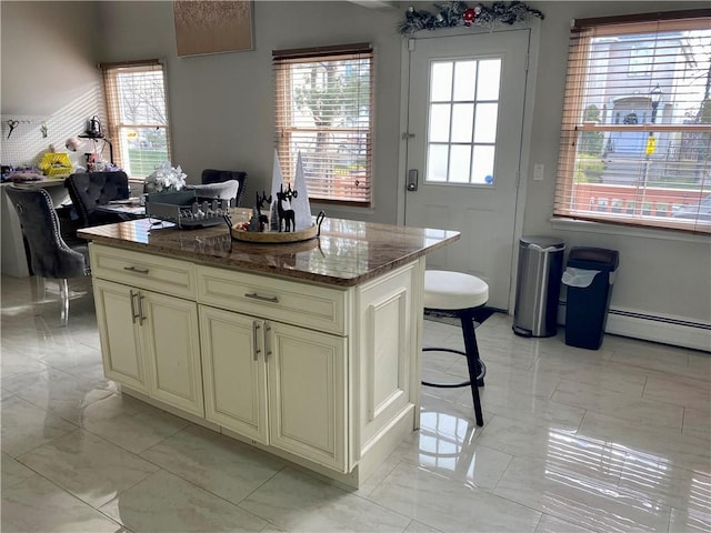 kitchen with dark stone counters, a wealth of natural light, marble finish floor, and cream cabinets