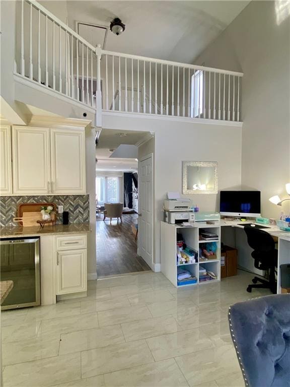 interior space with beverage cooler, marble finish floor, and a high ceiling