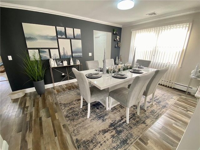 dining room with wood finished floors, a baseboard heating unit, ornamental molding, baseboards, and visible vents
