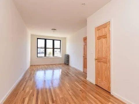 empty room with radiator heating unit and light hardwood / wood-style floors