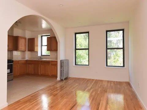 kitchen with stove, backsplash, radiator heating unit, and light hardwood / wood-style floors