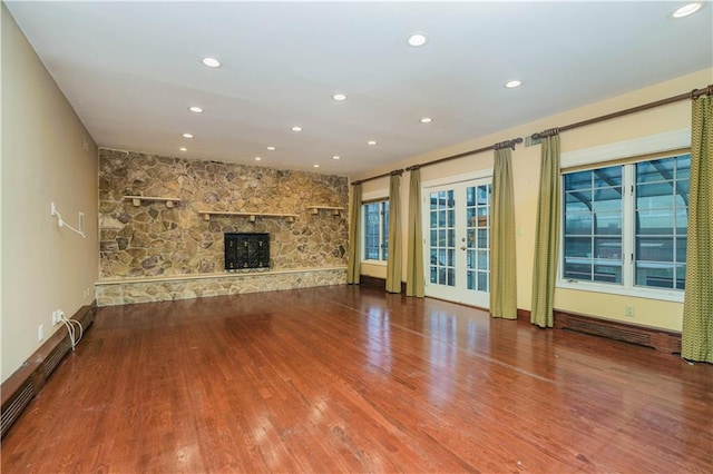 unfurnished living room with baseboards, a stone fireplace, wood finished floors, and recessed lighting