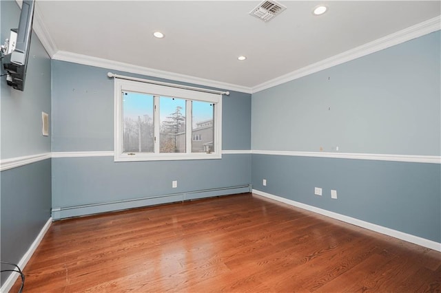 empty room with a baseboard heating unit, ornamental molding, wood finished floors, and recessed lighting